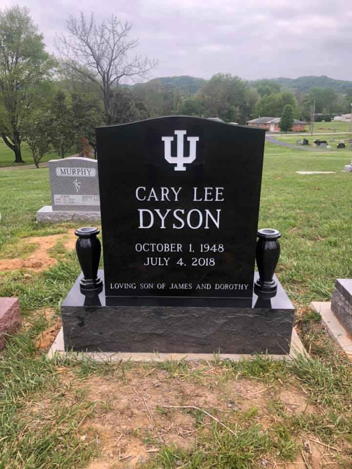 Cary Lee Dyson black granite monument standing against the green cemetery grounds